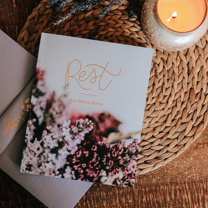 Cover of Rest Bible study. The study has lilacs on and is sitting on top of a Bible and next to a candle.  