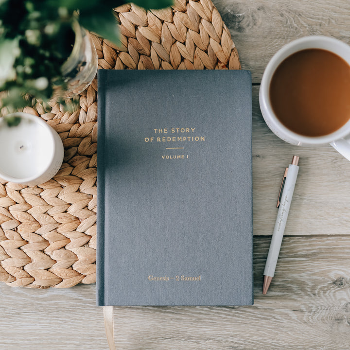 journal on table next to coffee mug and pen