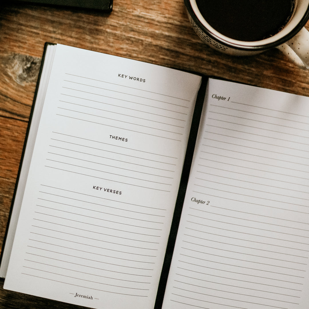 journal opened to lined pages next to coffee mug