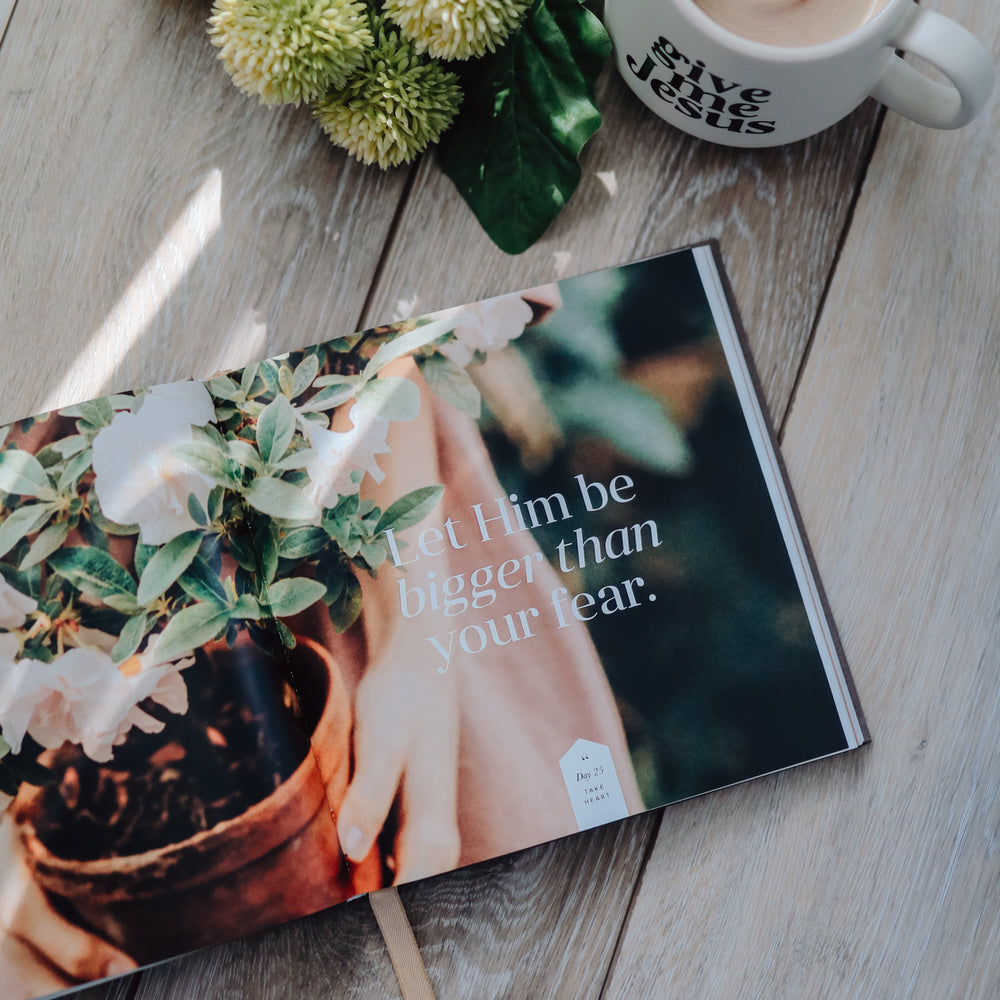 Devotional book open on a table next to a cup of coffee