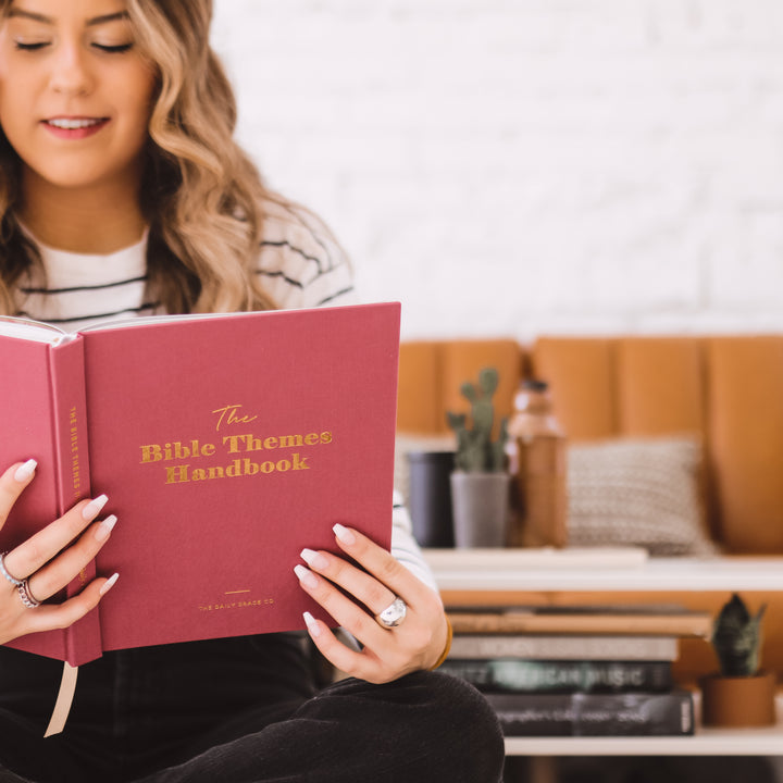 Woman reading through handbook showing cover to camera