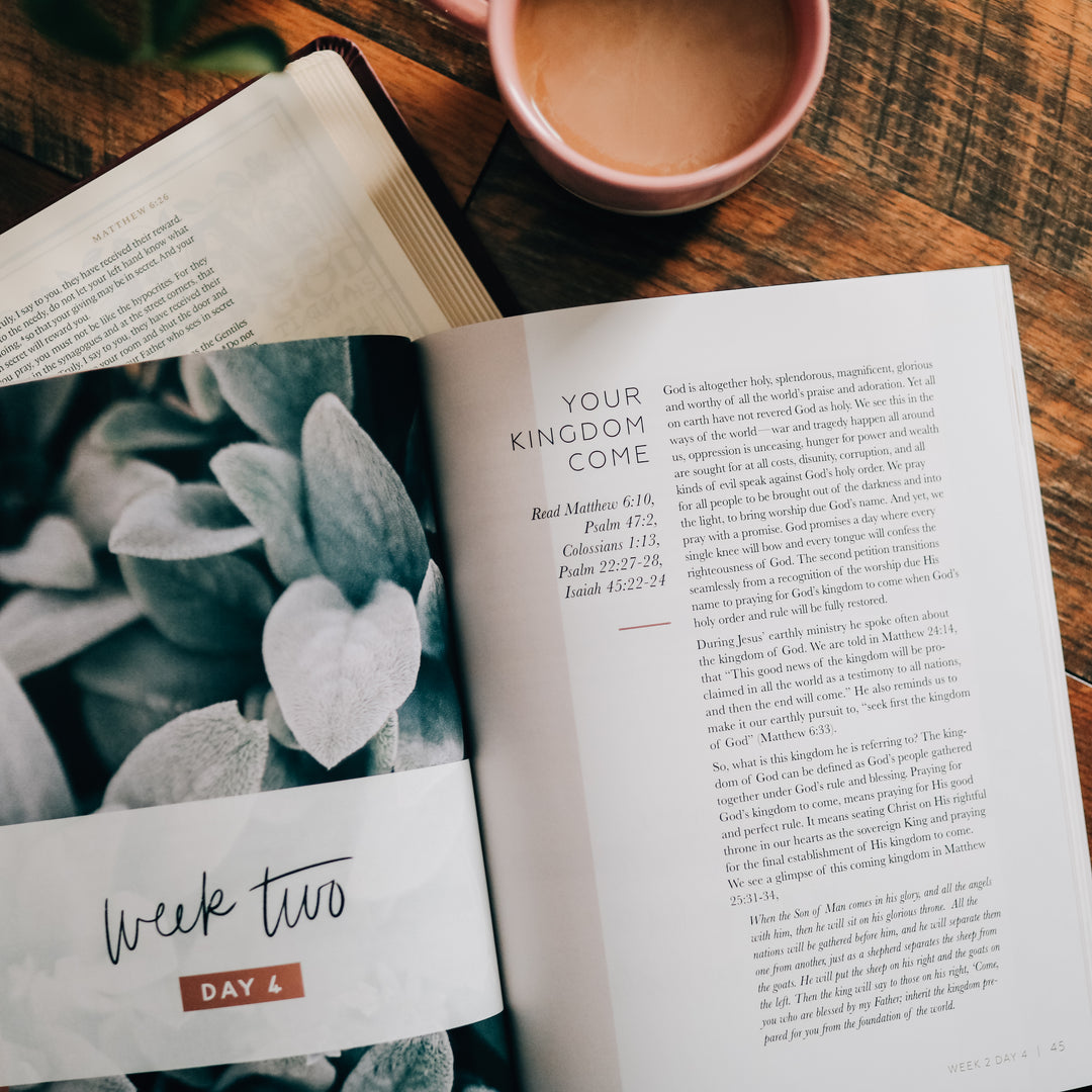 Bible Study open to weekly writing with coffee mug next to it