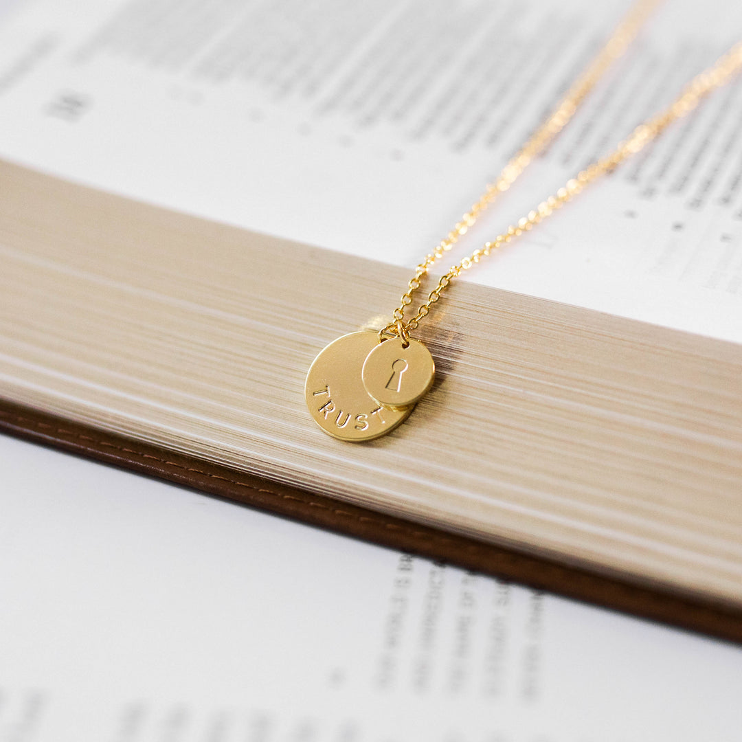 up close photo of necklace with 2 discs laying on a Bible